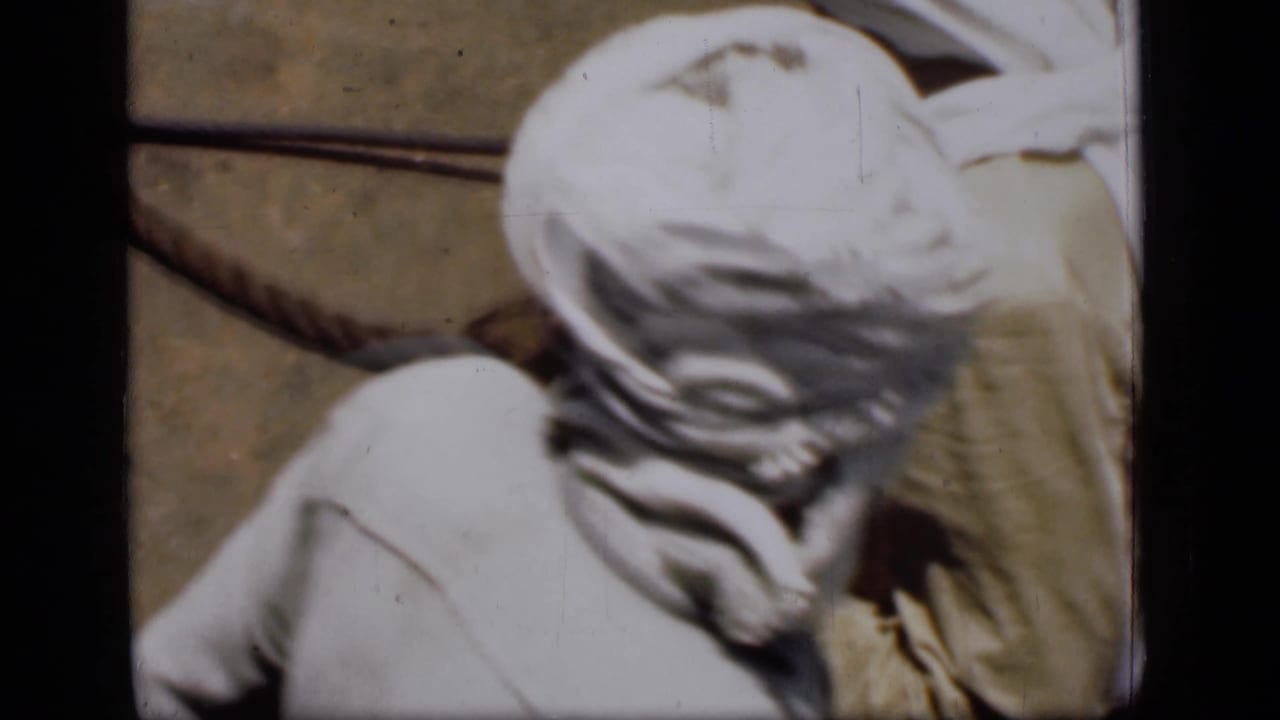 Overhead view of a man in a white head covering near the edge of a boat.