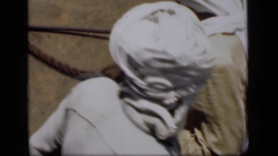 Overhead 1946 Suez Canal view of a man in a white head covering beside the boat edge and deck fittings.