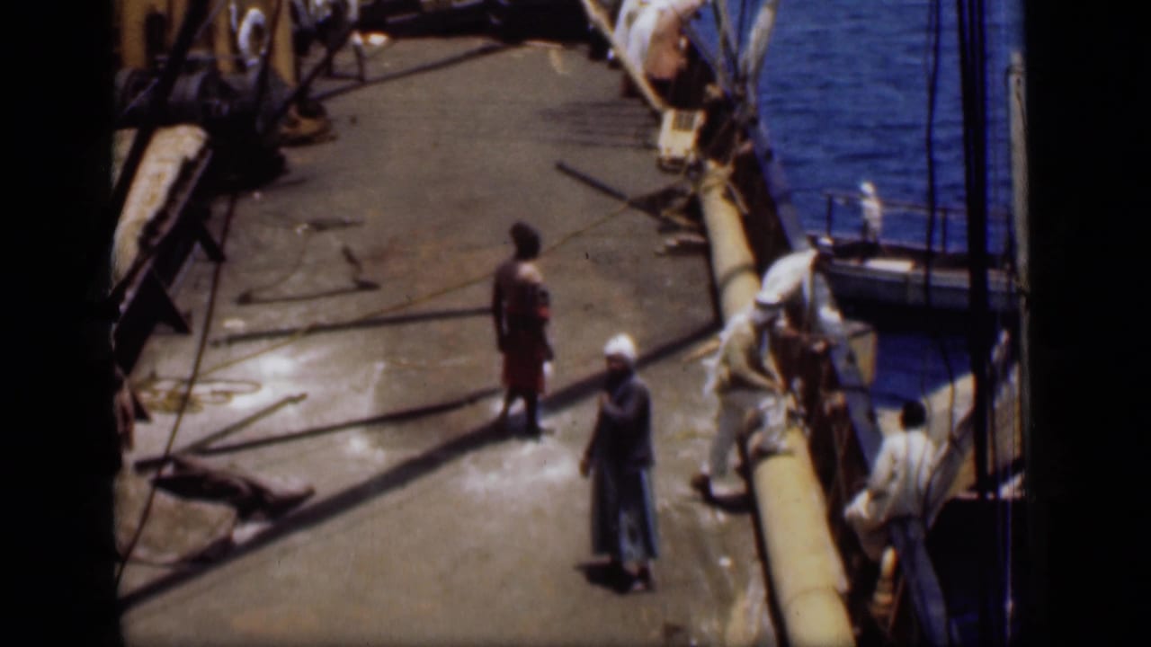 Wider 1946 Suez Canal boat-deck frame with several men, ropes, railings and blue water along the vessel.