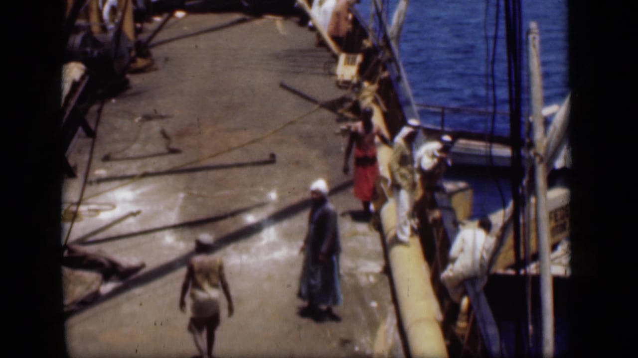 1946 Suez Canal home-movie view of men clustered along a dock beside a small boat and canal water.