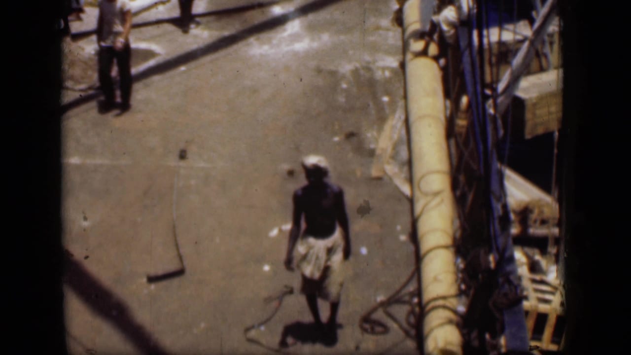 1946 Suez Canal frame showing a man walking across the pier with ropes, rigging, and boat equipment nearby.