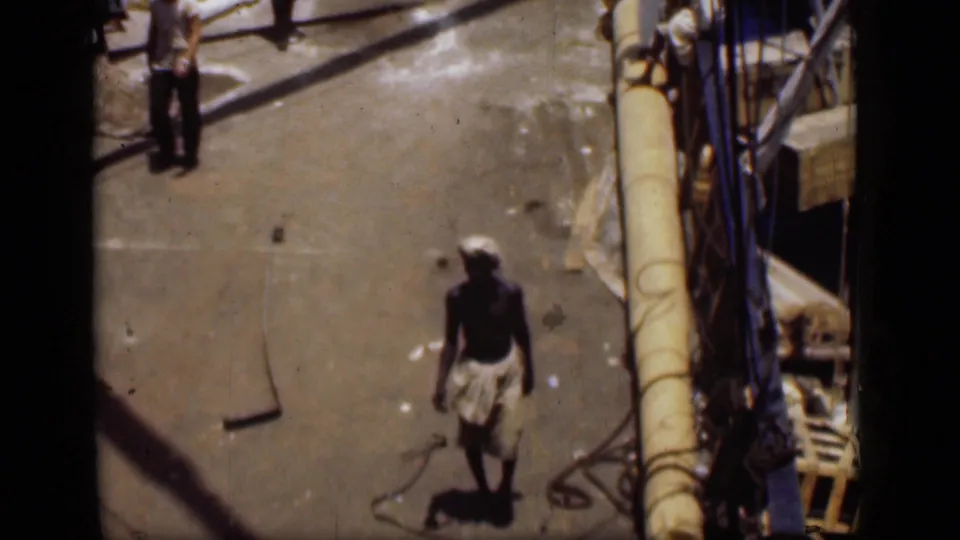 1946 Suez Canal frame showing a man walking across the pier with ropes, rigging, and boat equipment nearby.
