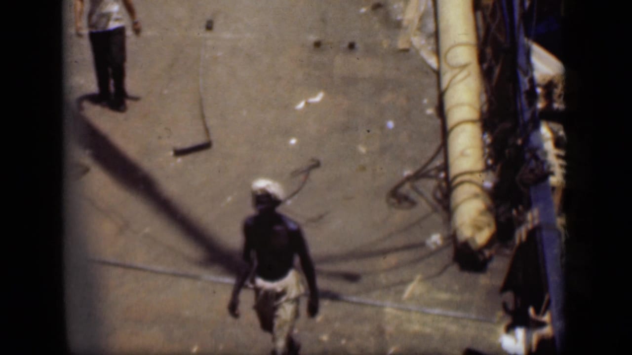 A man in a white headwrap moves along the deck of a boat in Suez Canal home-movie footage from 1946.