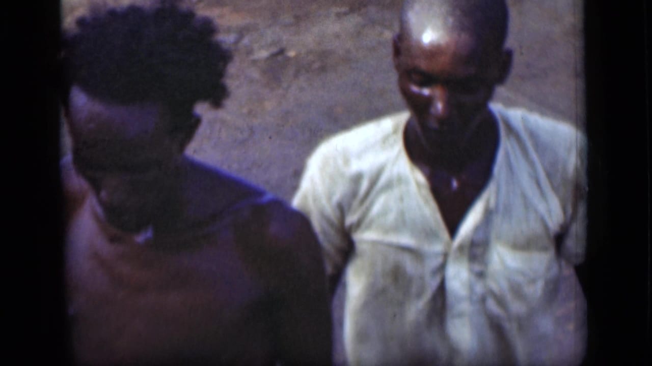 In 1946 8mm home-movie footage, two men pass near the camera before the view shifts toward a port building.