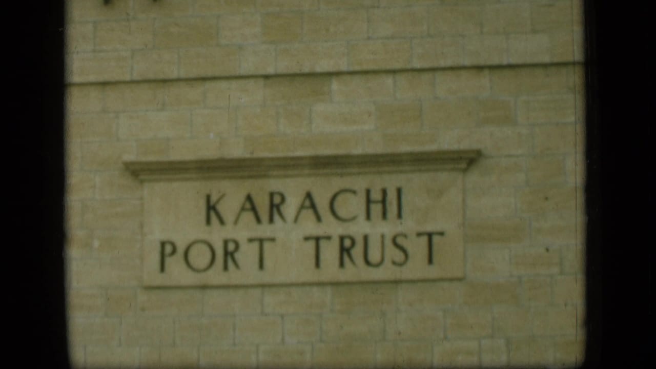 A stone building wall fills the frame, centered on a carved sign reading Karachi Port Trust.