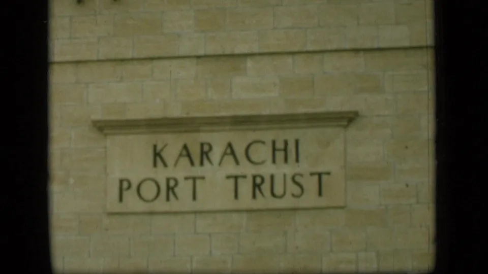 A stone building wall fills the frame, centered on a carved sign reading Karachi Port Trust.