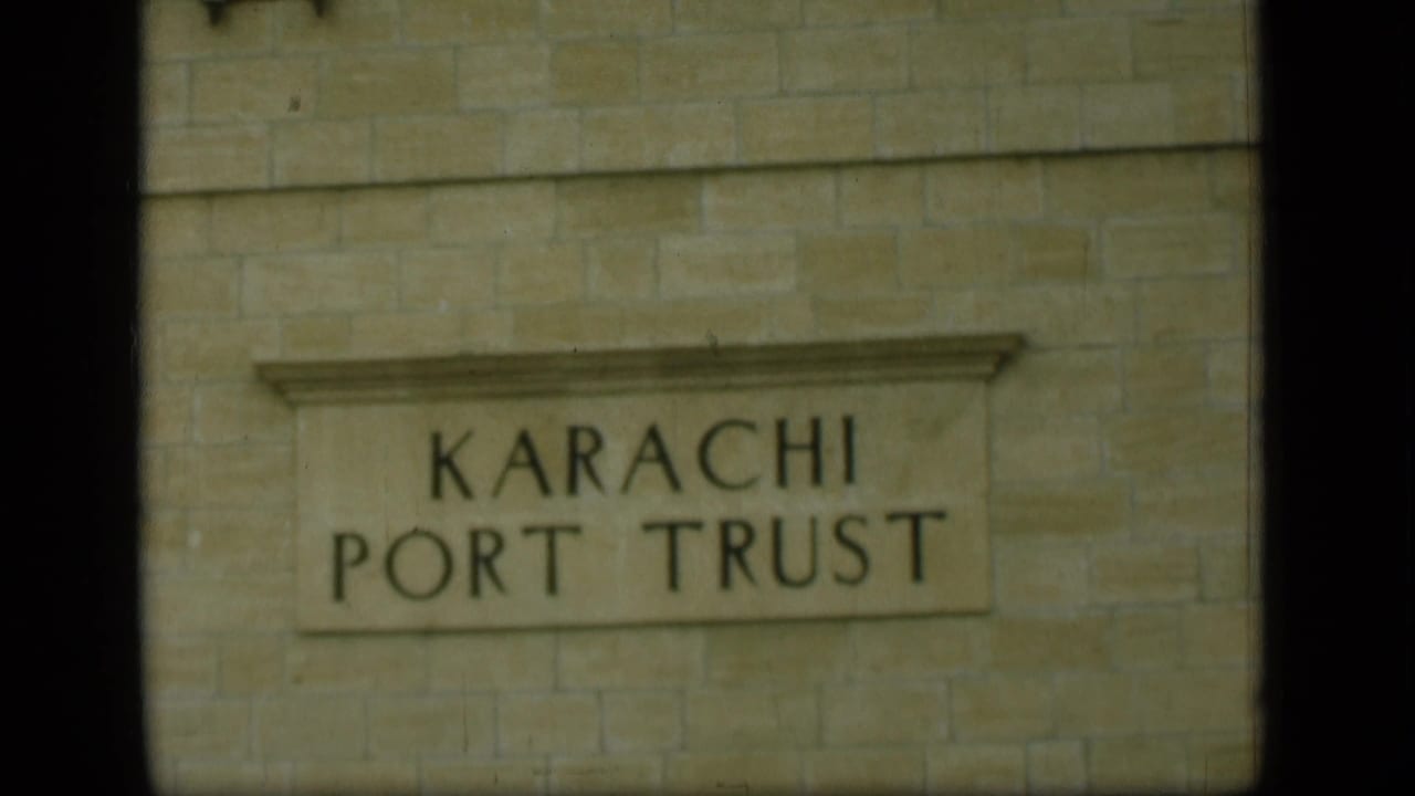 The final frame holds on the Karachi Port Trust sign, with dark frame edges and soft 8mm color.