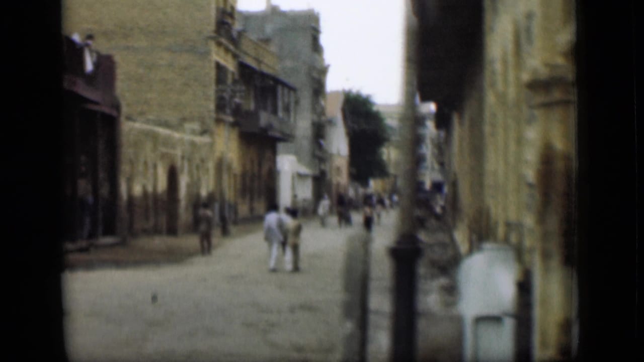 1946 8mm street view, supplied as Suez Canal, Egypt, showing pedestrians on a narrow road lined with worn building fronts.