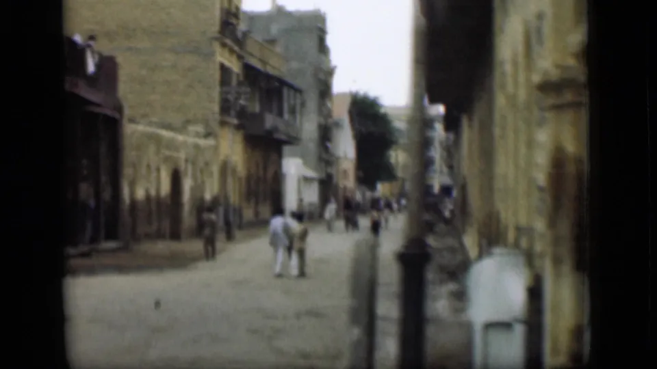 1946 8mm street view, supplied as Suez Canal, Egypt, showing pedestrians on a narrow road lined with worn building fronts.