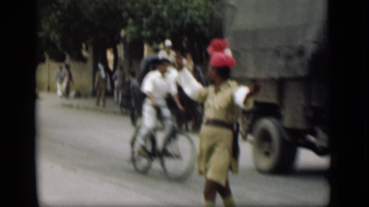 1946 street frame, supplied as Suez Canal, Egypt, with a man in a red headwrap gesturing near a bicycle, pedestrians and a large truck.