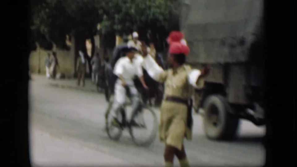 1946 street frame, supplied as Suez Canal, Egypt, with a man in a red headwrap gesturing near a bicycle, pedestrians and a large truck.