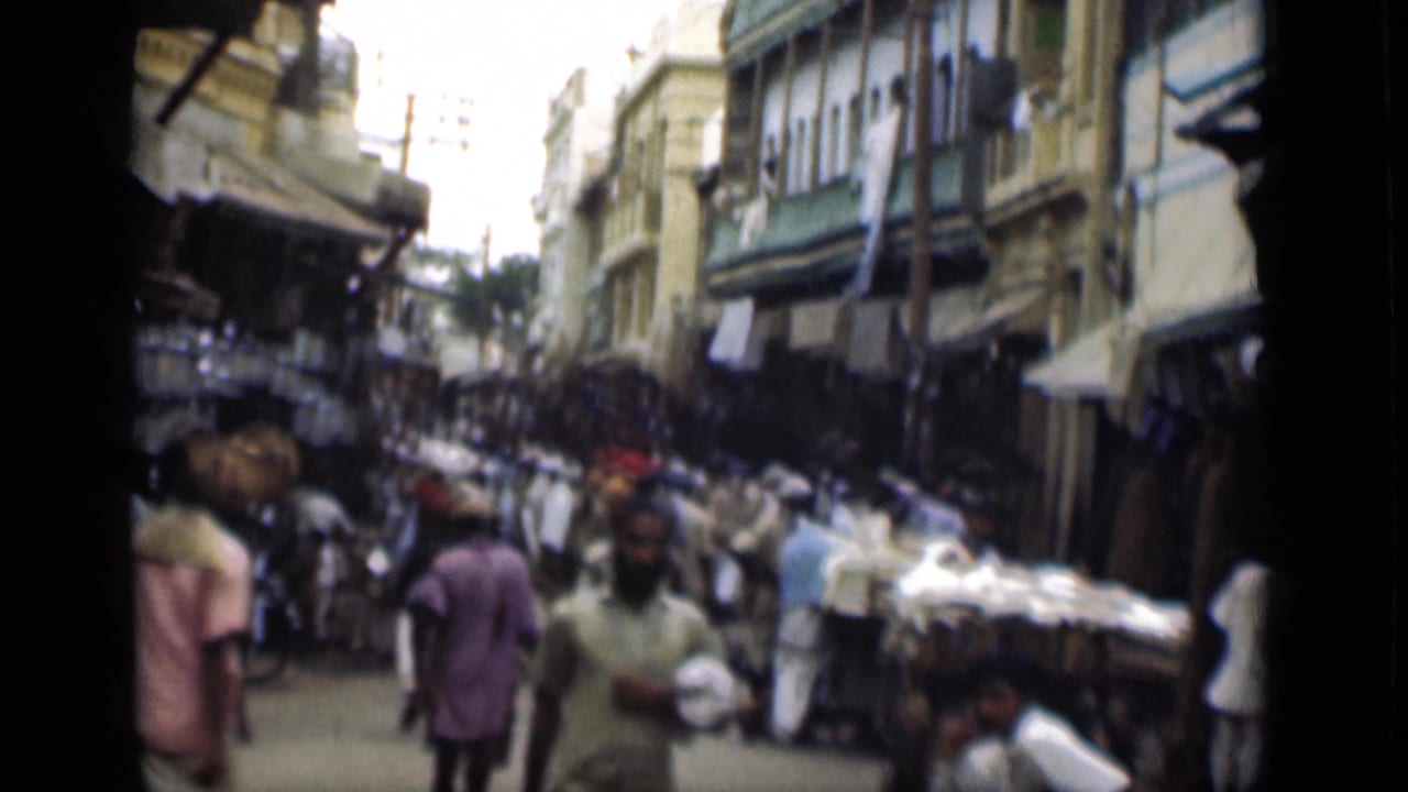 Crowded 1946 Egypt street view showing pedestrians, vendors, carts, and shaded shopfronts along a narrow lane.