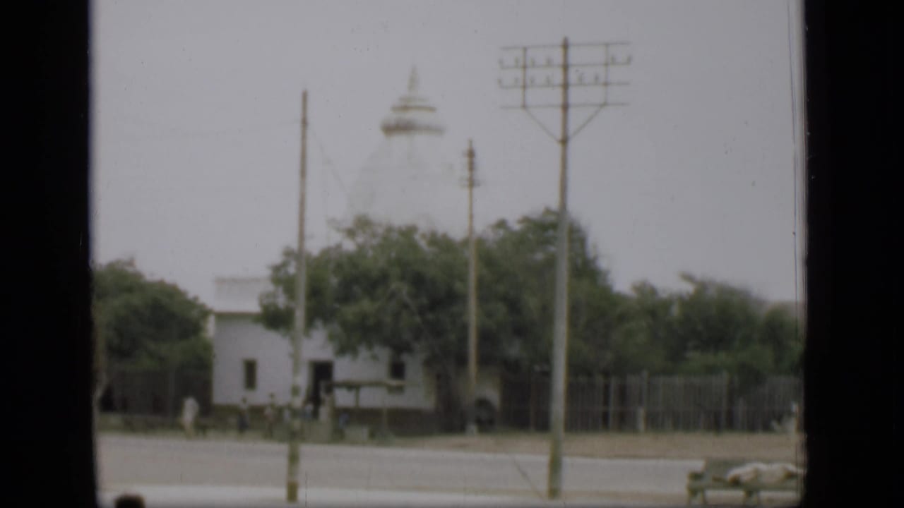 1946 Suez Canal area exterior with a white domed church or temple, roadside poles, trees, fencing, and a partial car.
