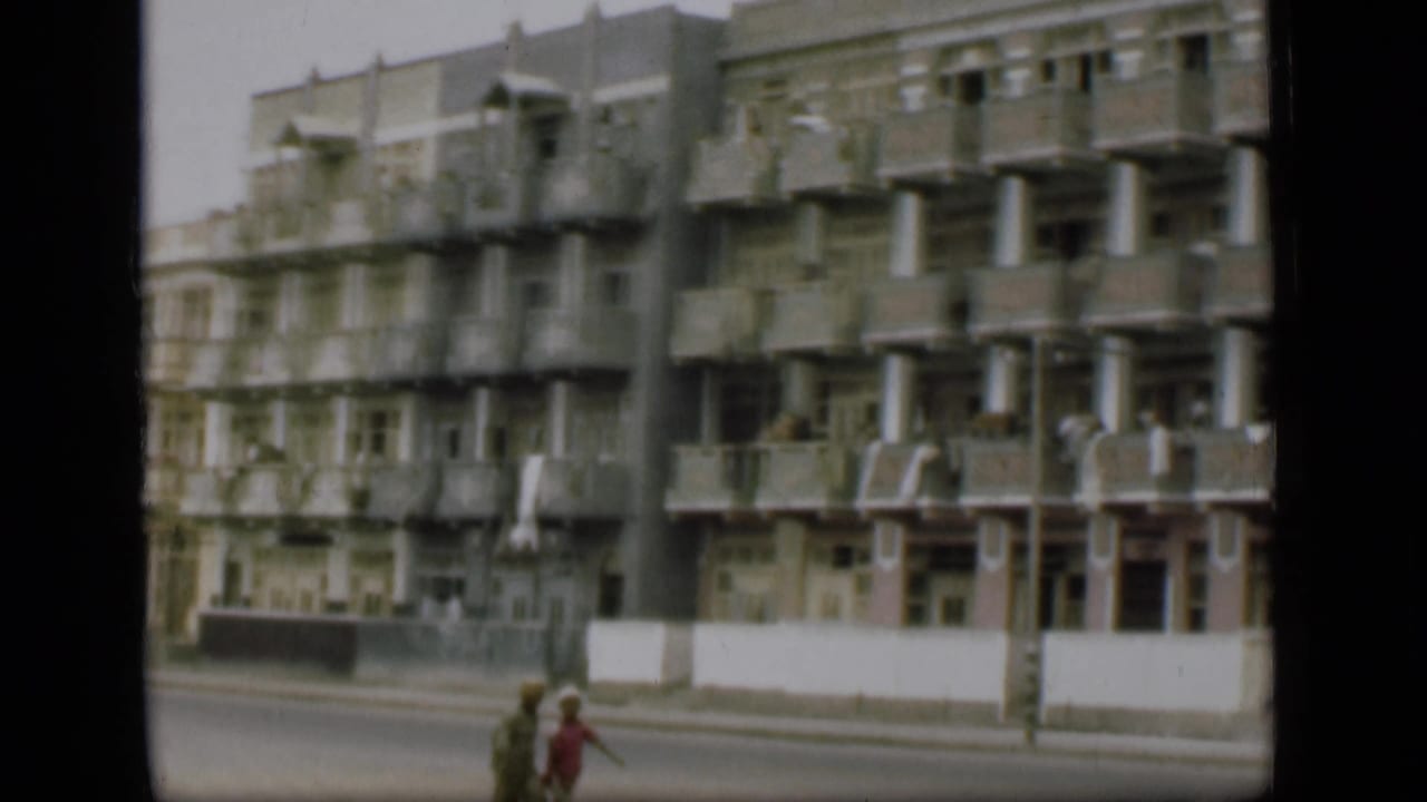 A 1946 Suez Canal area street view shows a high-rise apartment building with repeating balconies and pedestrians below.