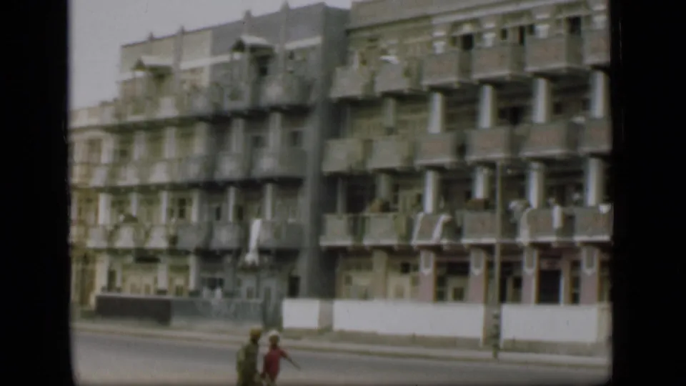 A 1946 Suez Canal area street view shows a high-rise apartment building with repeating balconies and pedestrians below.
