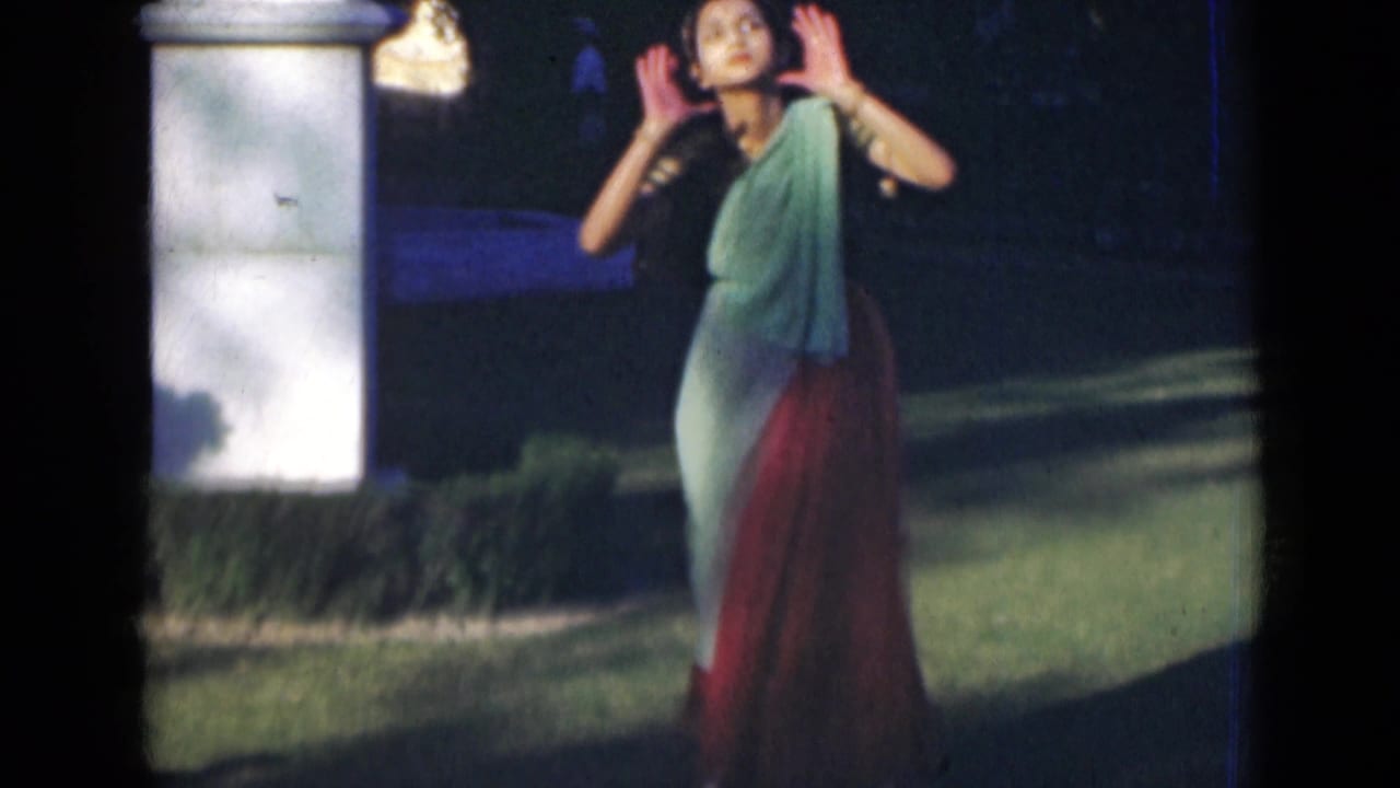 Woman in a saree dancing on a lawn near a white pillar.