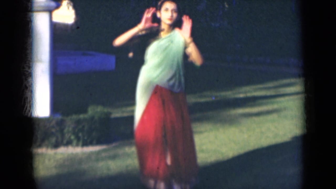 Woman in a saree faces the camera with both hands raised outdoors.