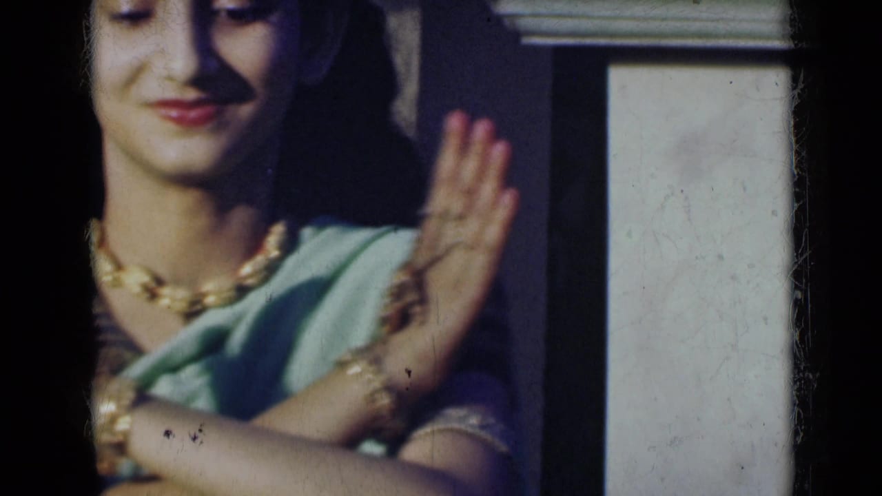 Young woman in a light green sari raises one hand beside her face.