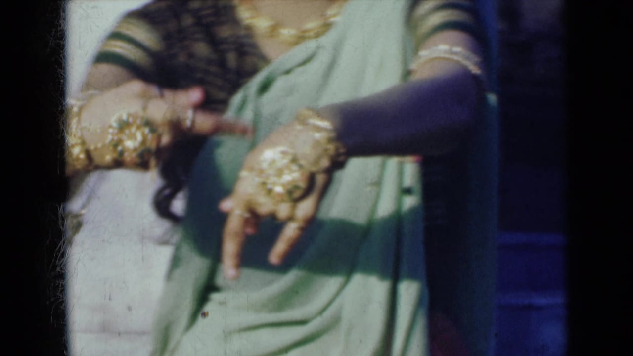 Close view of a woman in a light green sari moving jewelry-covered hands.
