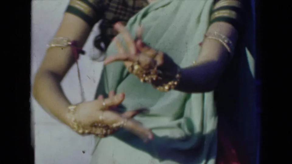 Close 8mm view from India in 1947 of a woman's hands and forearms forming a dance gesture over a light green sari.