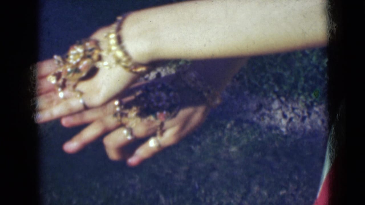 A close-up shows hands and a forearm with gold-toned bangles, rings, and hand jewelry in 1947 India home-movie footage.