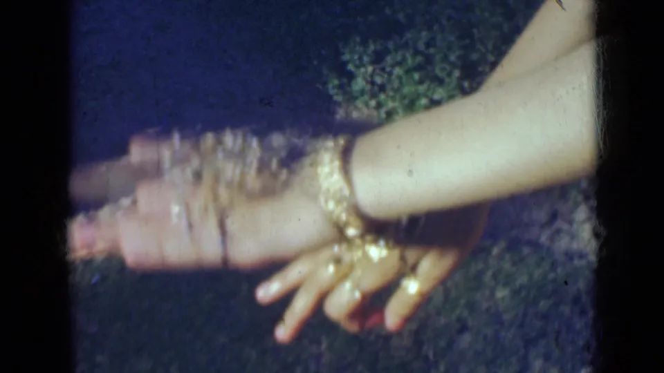 Motion blur catches the woman's hands as she moves her rings and bangles for the 8mm camera in India, 1947.