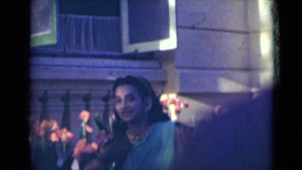 Woman in teal clothing dancing near orange flowers and a stone railing.