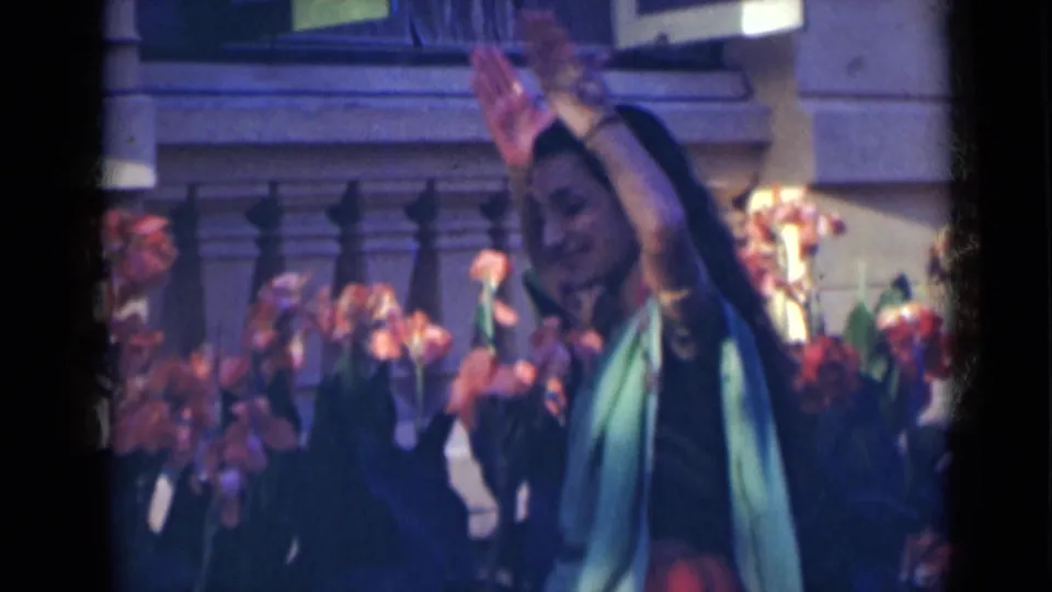 A woman continues a traditional dance gesture with lifted hands in 1947 India home-movie footage.