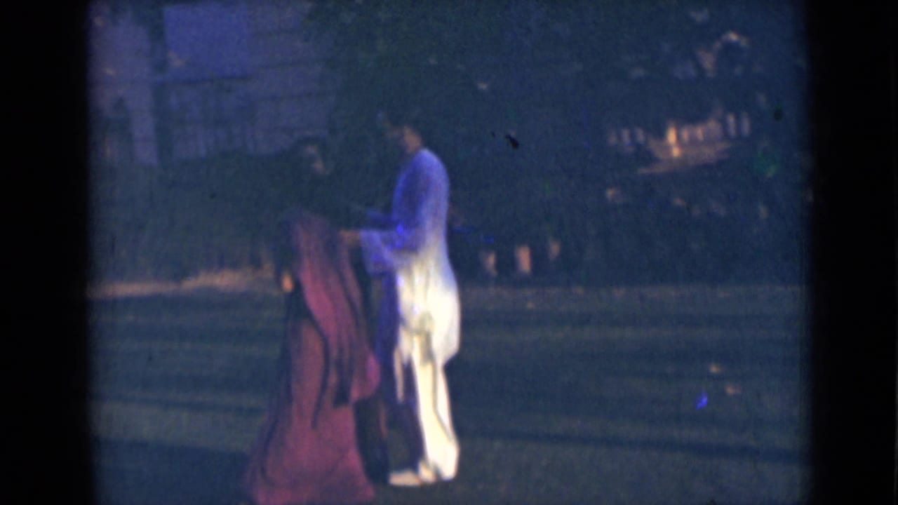 Two adults continue walking in the India 1947 street scene, with a saree and light kurta visible against a dark tree-lined background.