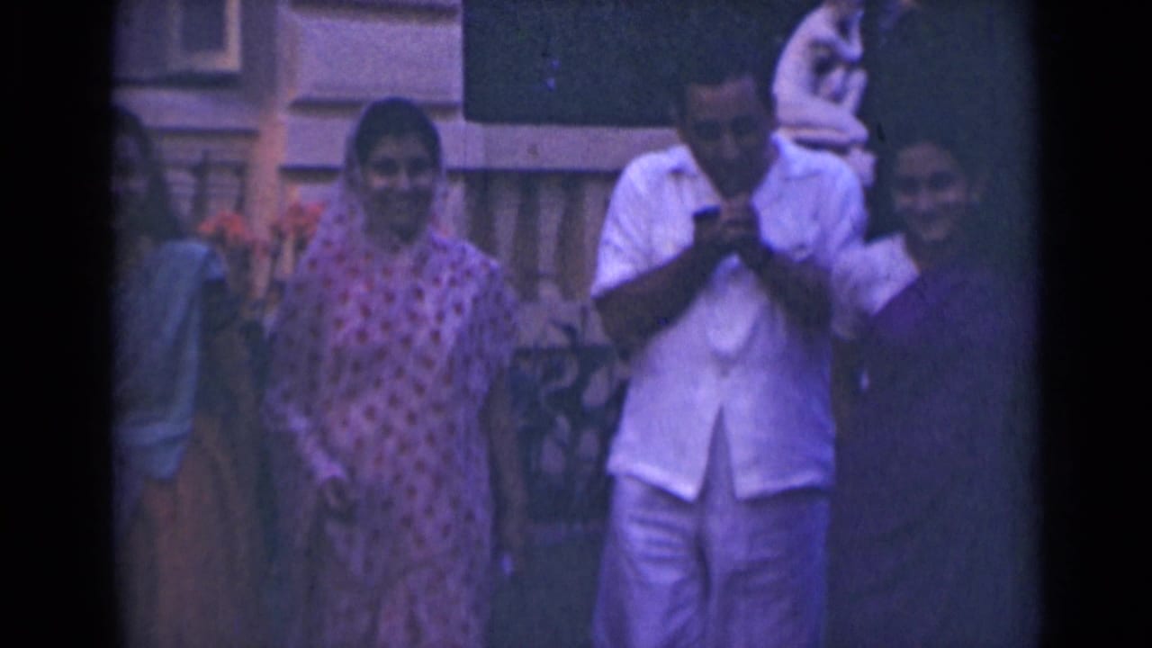 In 1947 India home-movie footage, three women and a man in white clothing stand outdoors before a building facade.