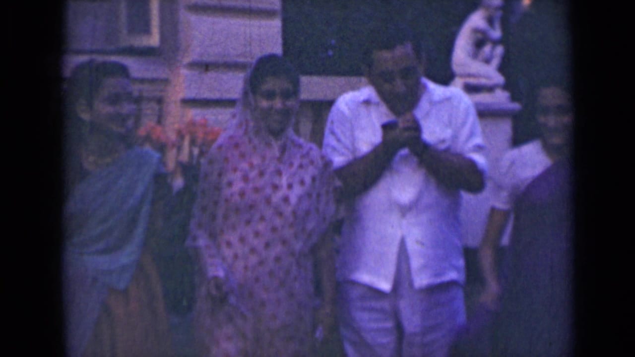 A group stands close together outside, with the man still holding an object near his mouth.