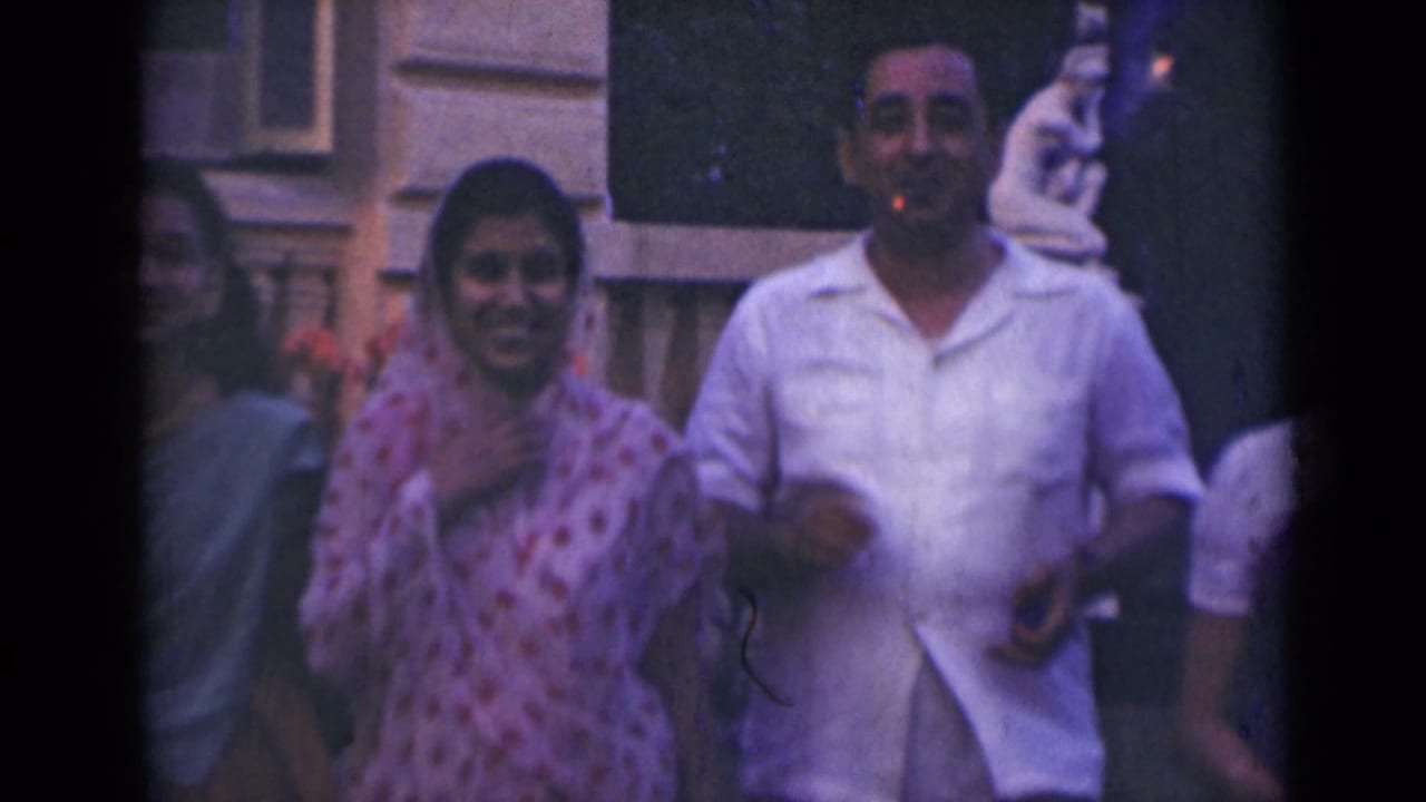 Adults smile toward the camera outside a stone building with flowers behind them.