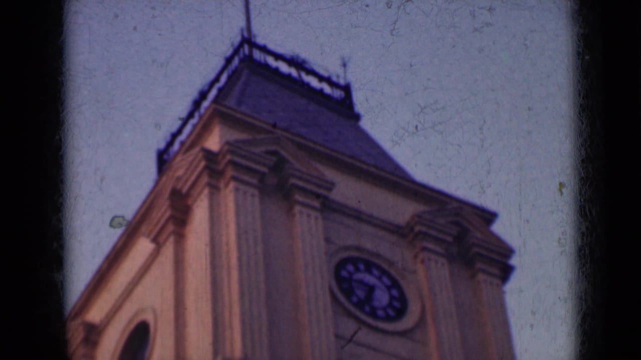 Clock tower facade seen from below with dark film edges.