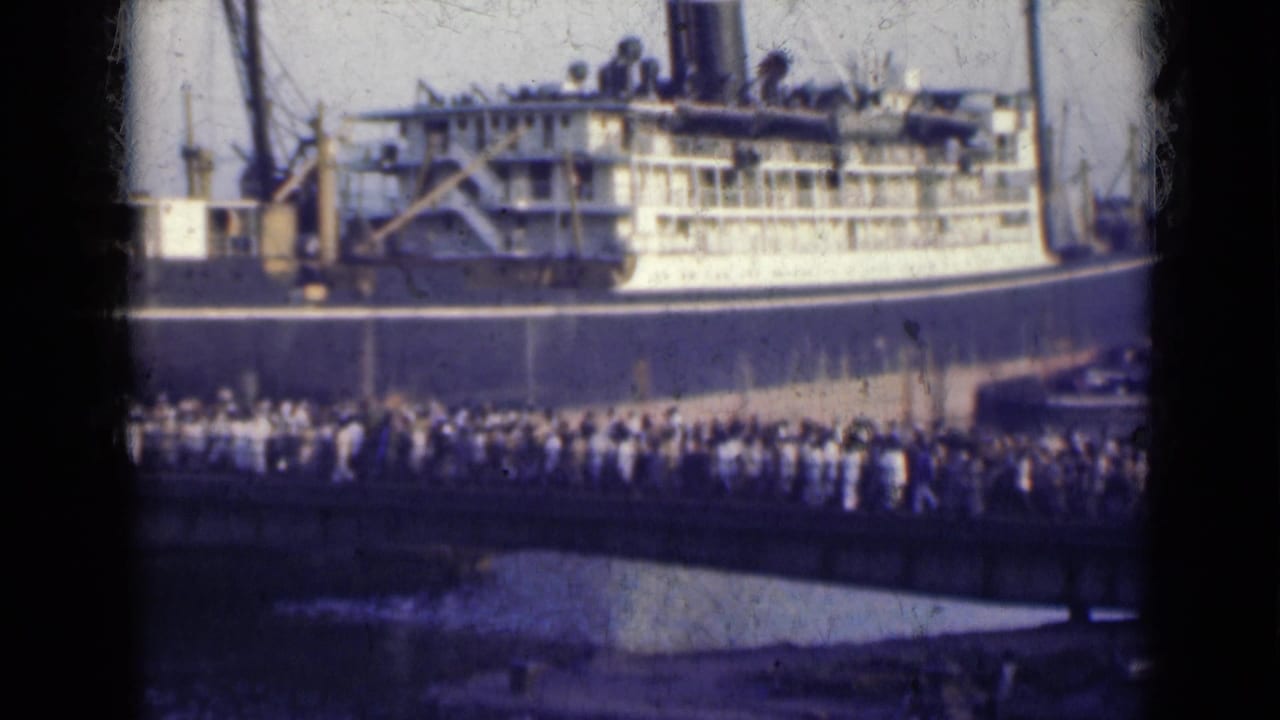 Large passenger ship behind a dense line of people on a bridge.