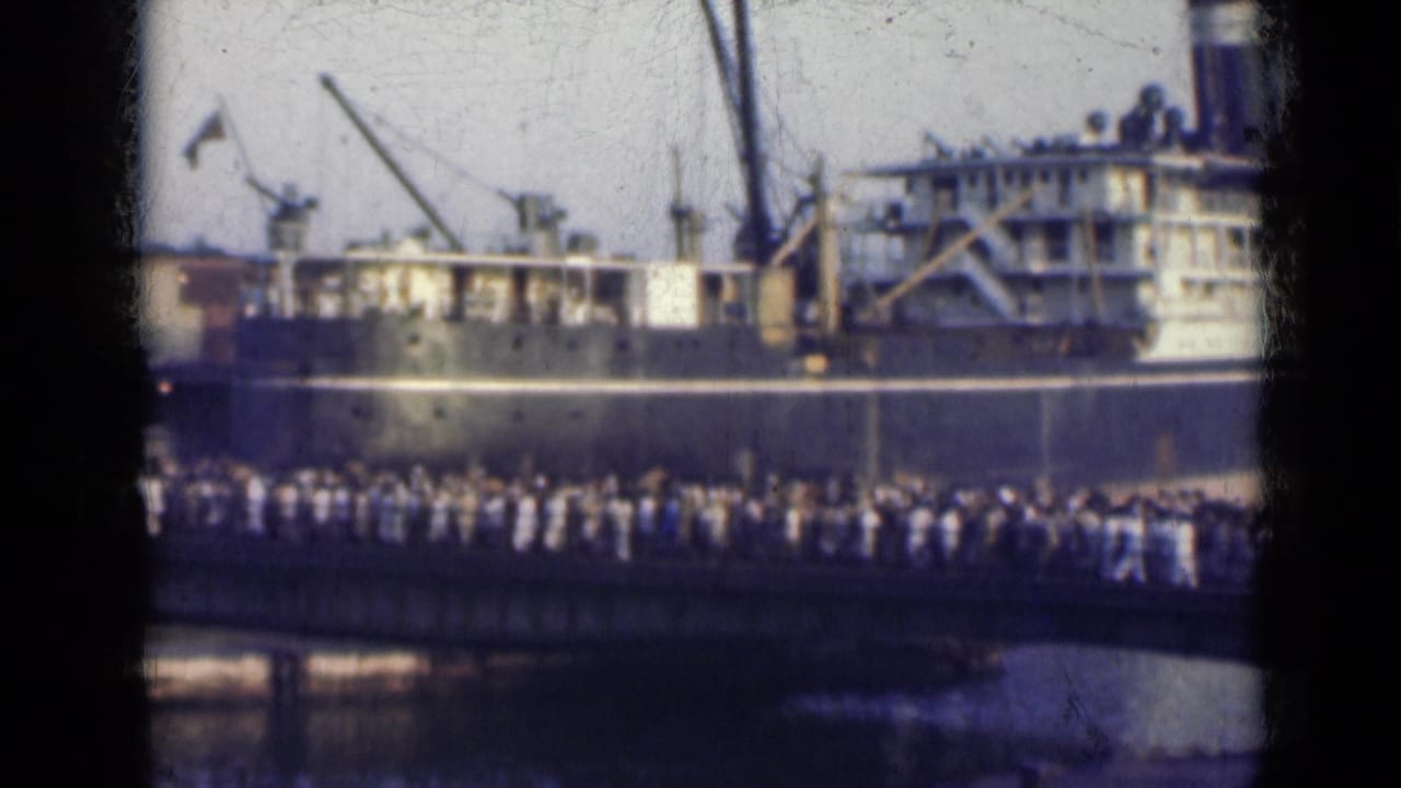 A crowd fills the bridge below a docked ship, seen through soft, faded 8mm framing in India in 1947.