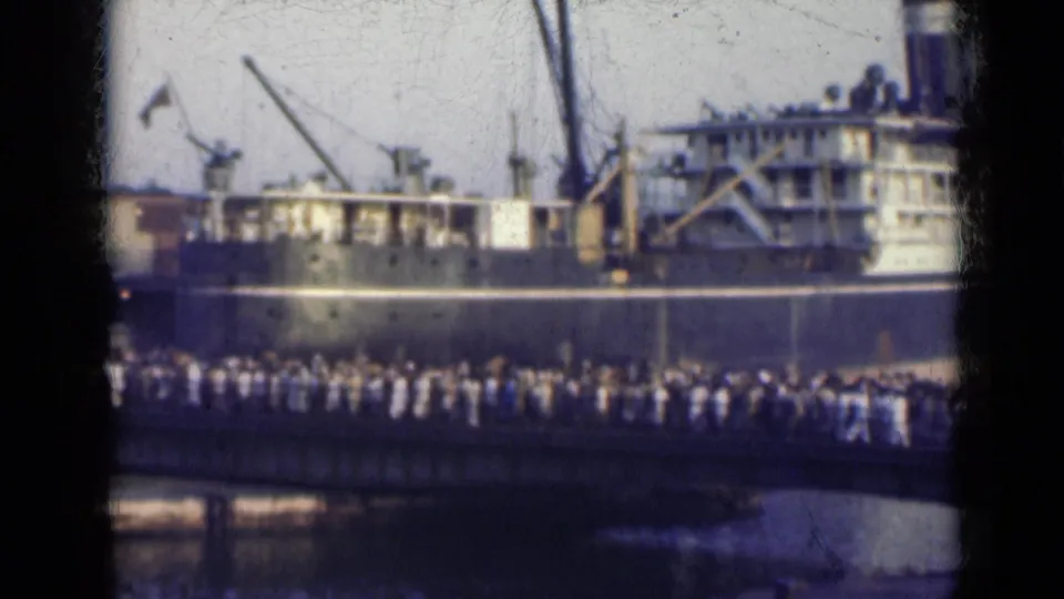 A crowd fills the bridge below a docked ship, seen through soft, faded 8mm framing in India in 1947.