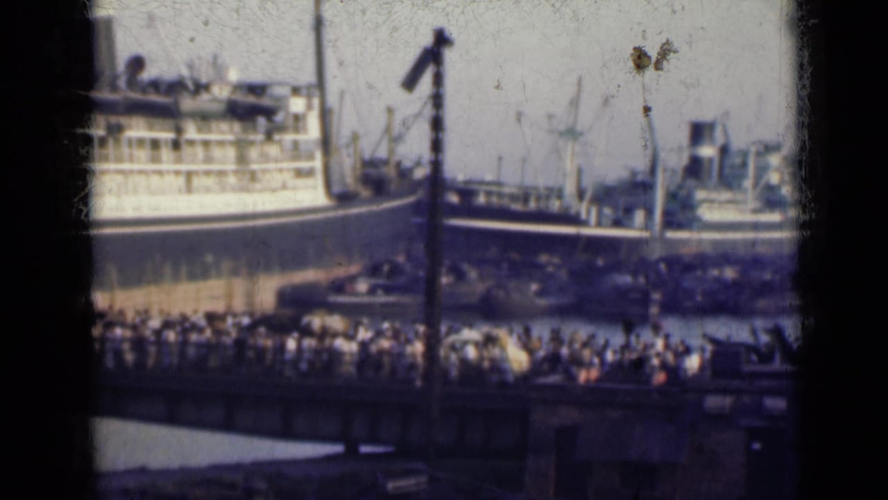 Crowded harbor scene with large ships, cranes, and passengers seen from a vessel.