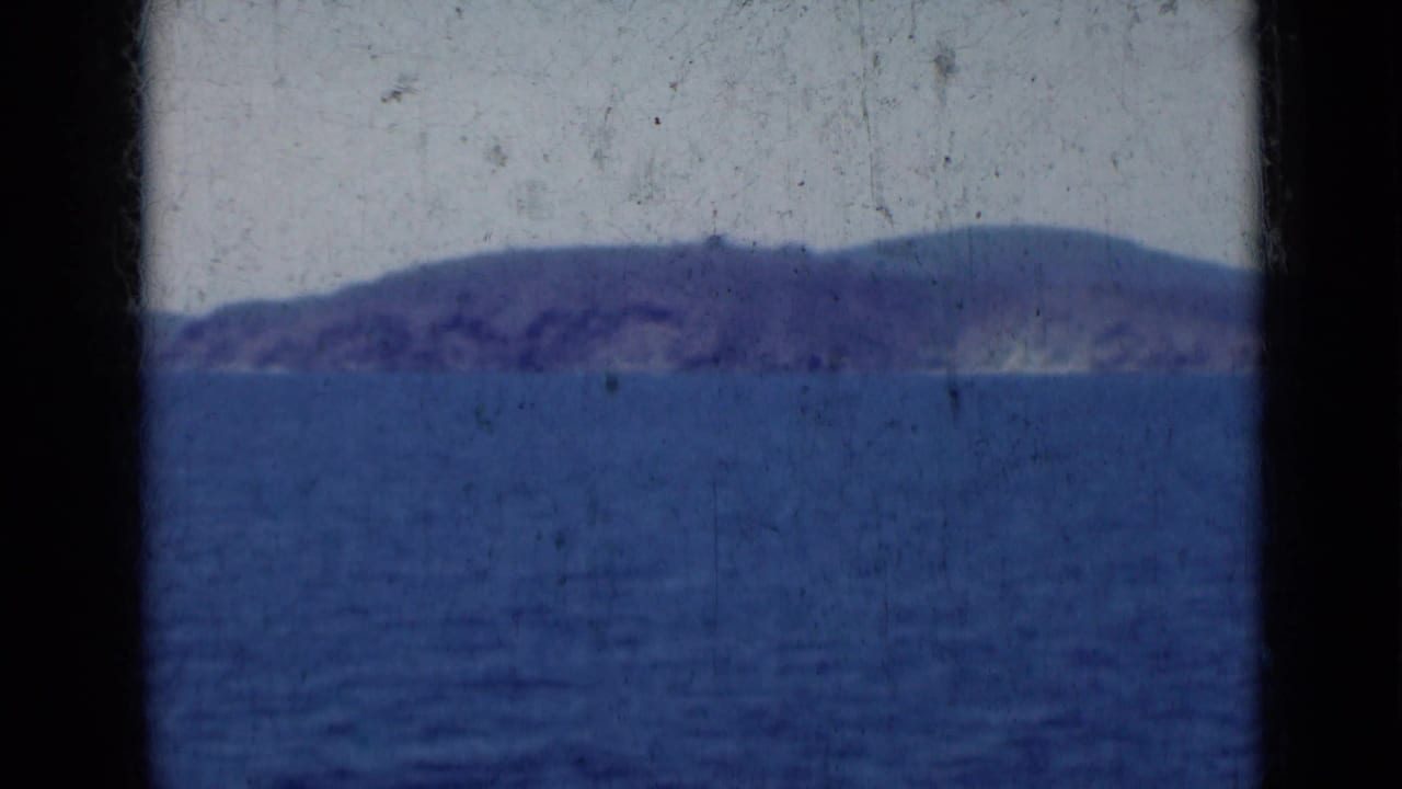 Hazy coastline stretches across the horizon above deep blue water with dark borders at the sides.