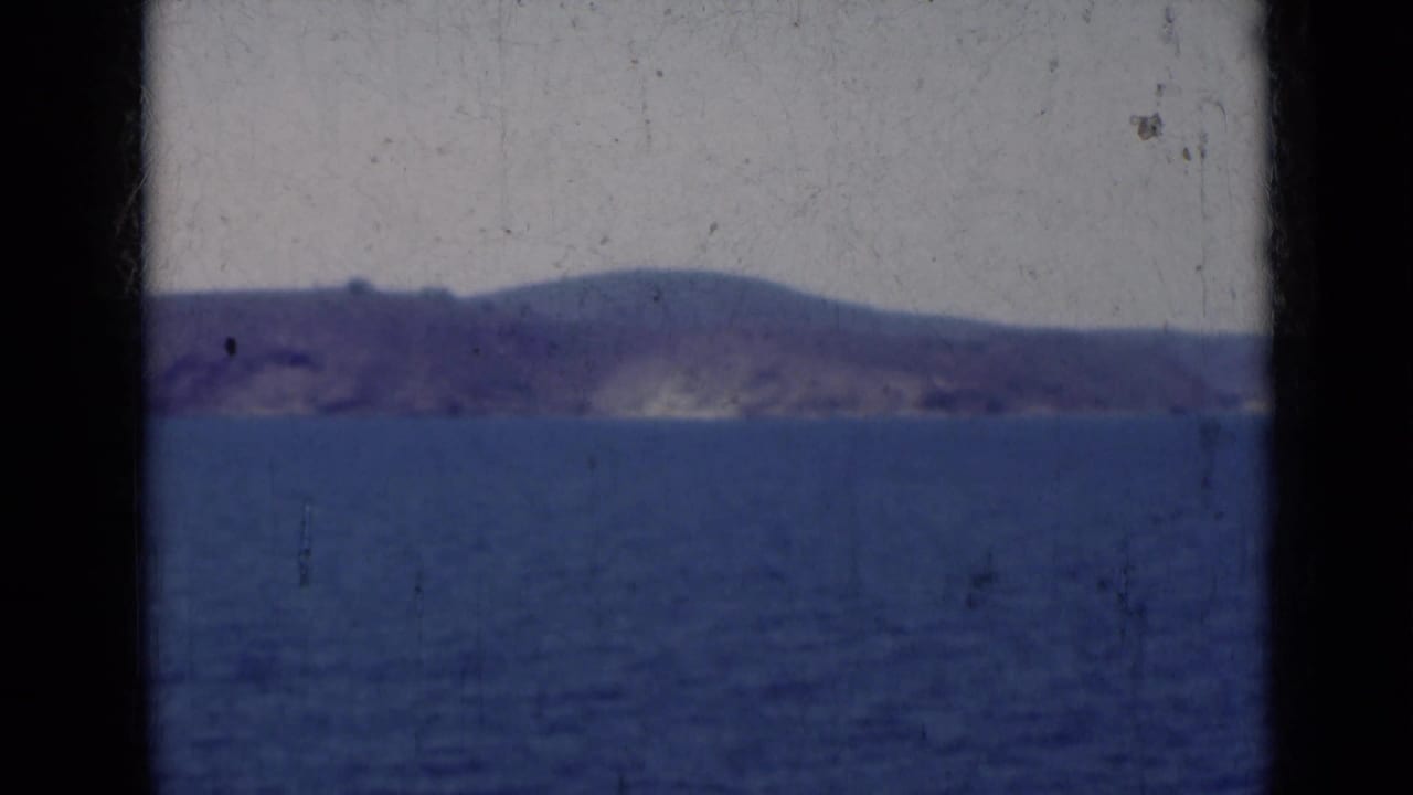 Distant landmass across blue water under a pale sky, framed by dark 8mm borders.