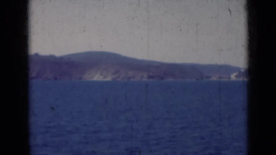 1947 India 8mm view of open water facing a low, hazy landmass with dark gate edges and visible film wear.