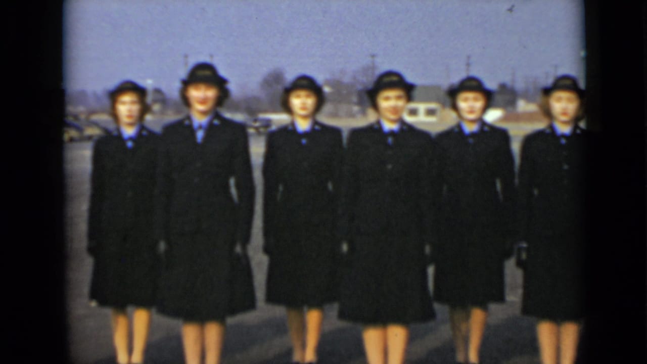 In New York in 1947, six women in dark military-style uniforms and brimmed hats stand in formation outdoors.