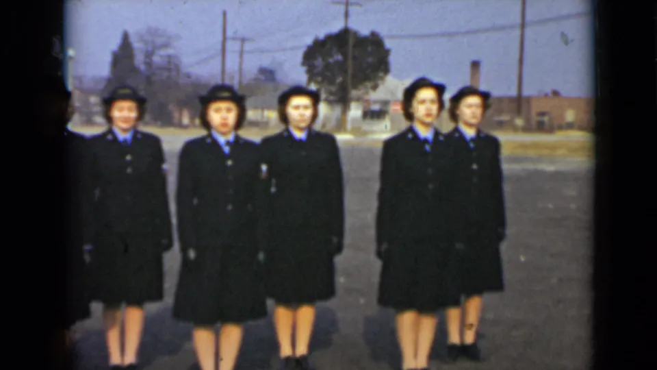 A smaller grouping of uniformed women stands in formation outdoors, with coats, hats, and blue shirts visible.