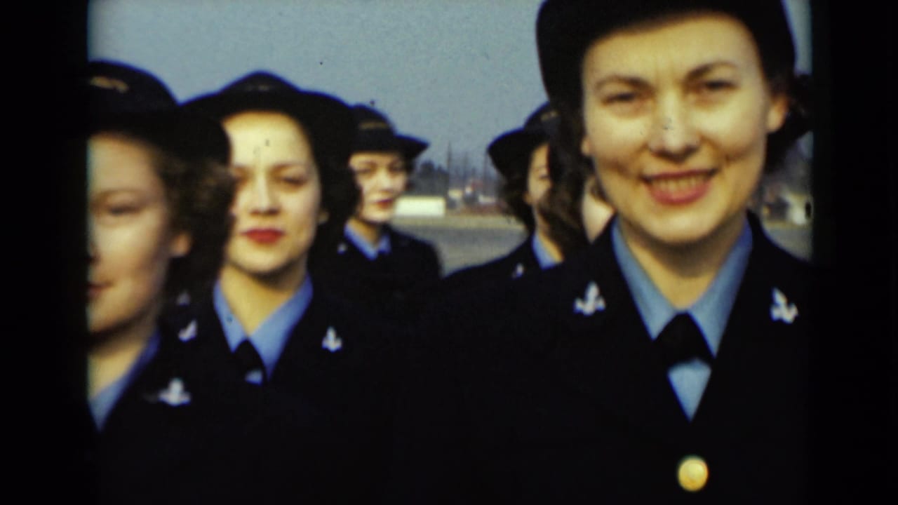 Women in dark blue uniforms and hats stand in formation outdoors.