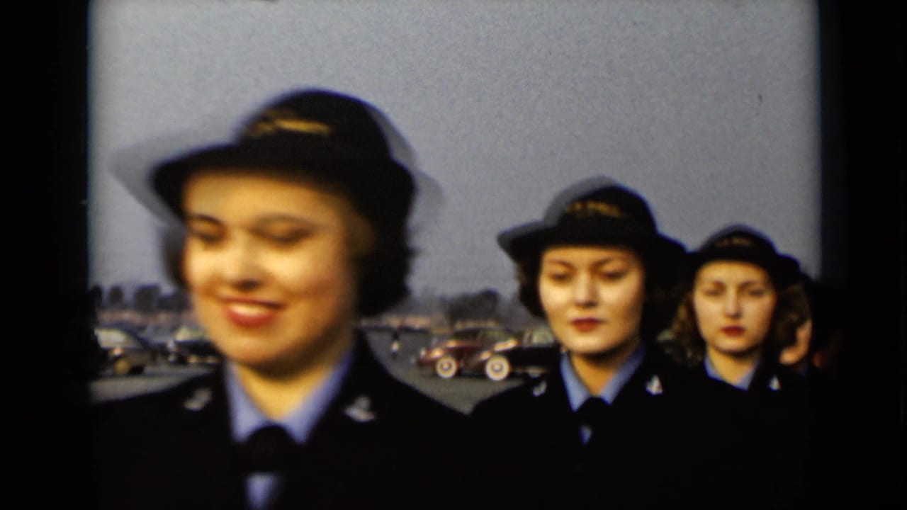 Uniformed young women in dark hats march in a line outdoors.