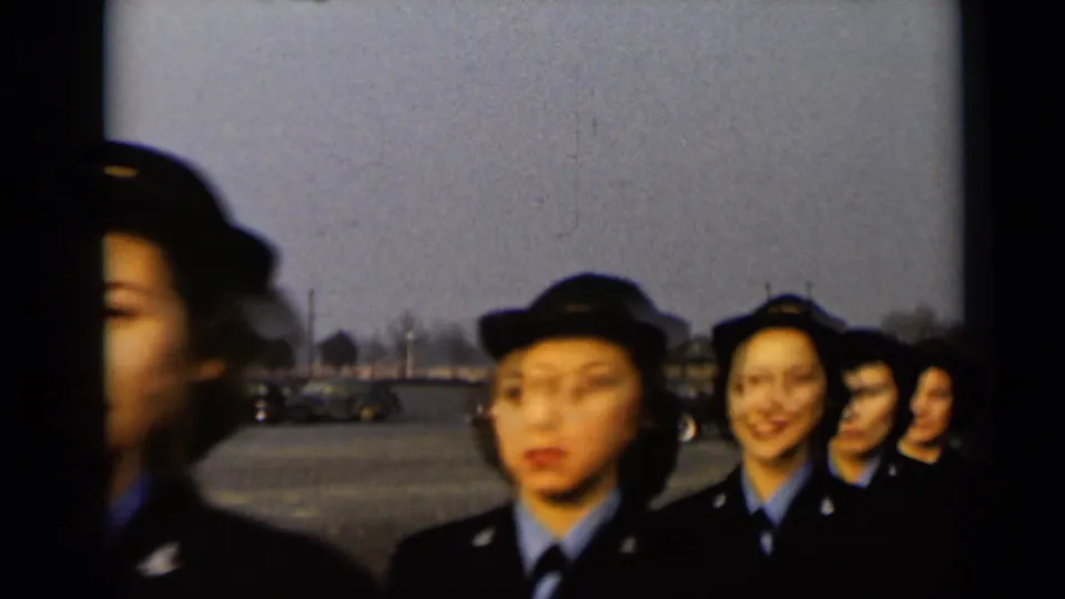 The marching line passes close by in soft-focus 8mm footage, showing uniformed women outdoors in New York in 1947.