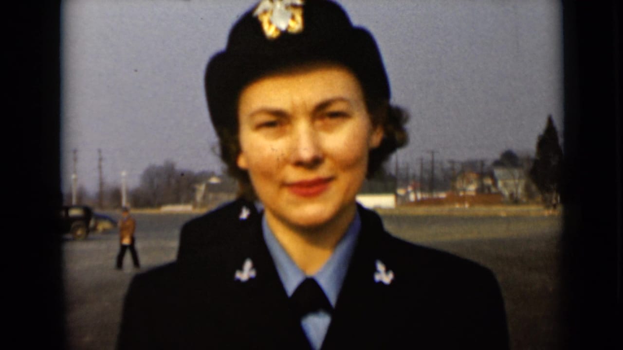 A young woman in a dark Navy-style uniform faces the camera in a paved lot.