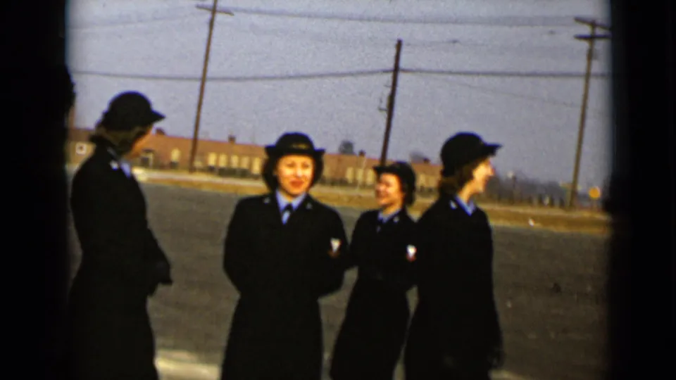 In 1947 New York footage, four uniformed women stand together on a paved field with utility poles and a brick building behind them.