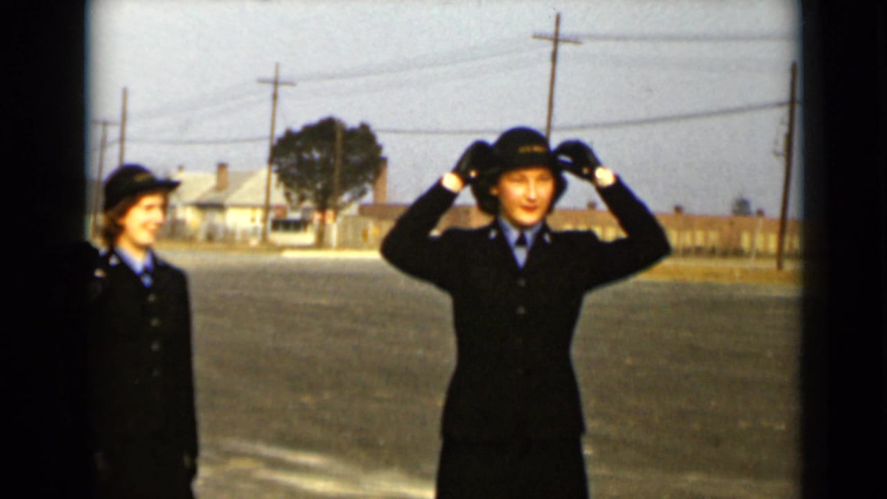 A uniformed woman adjusts her hat while another woman stands nearby on the street.