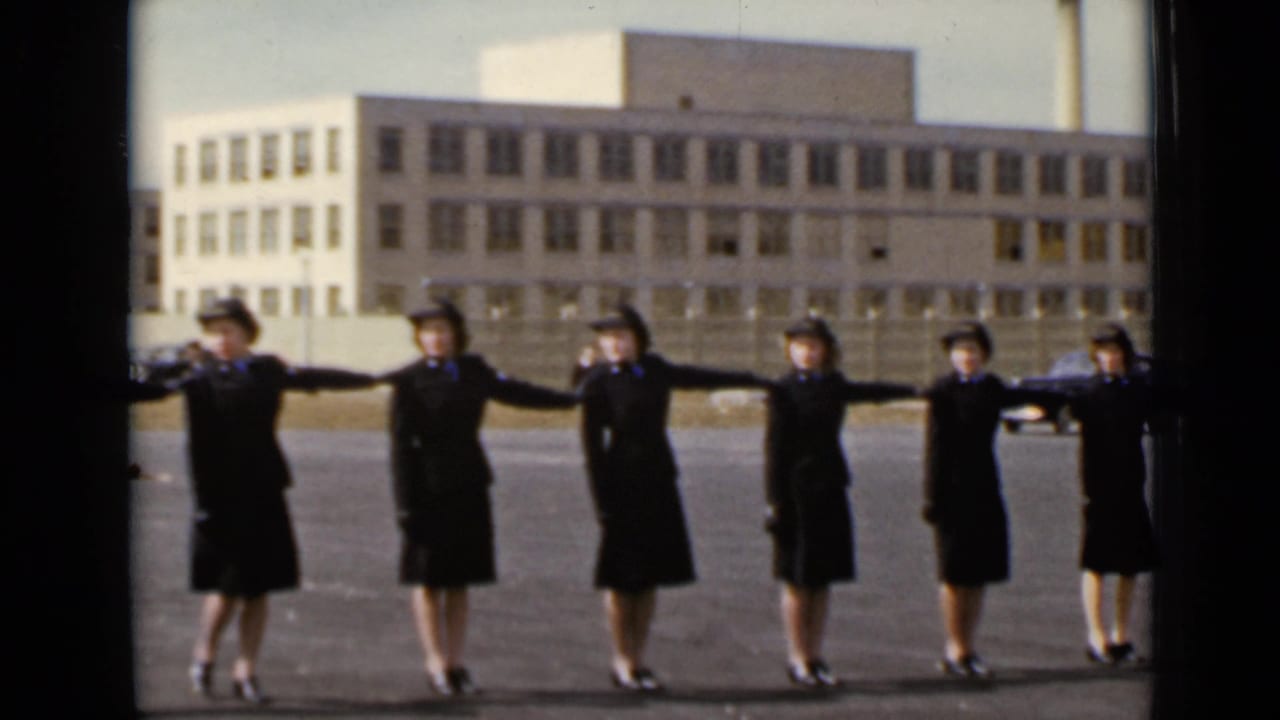 In 1947 New York footage, uniformed women extend their arms in a spacing drill before a large institutional building.