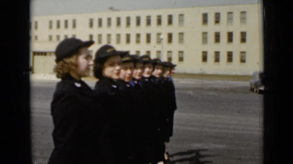 In New York 1947 footage, uniformed women stand at attention in a paved courtyard before an institutional building.